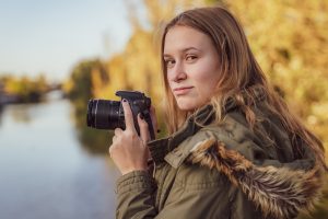Young Woman With Slr Camera In His Hand Is Looking Into Camera