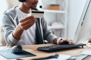 Ordering something online. Close up of young man in casual clothing making a purchase online while spending time at home