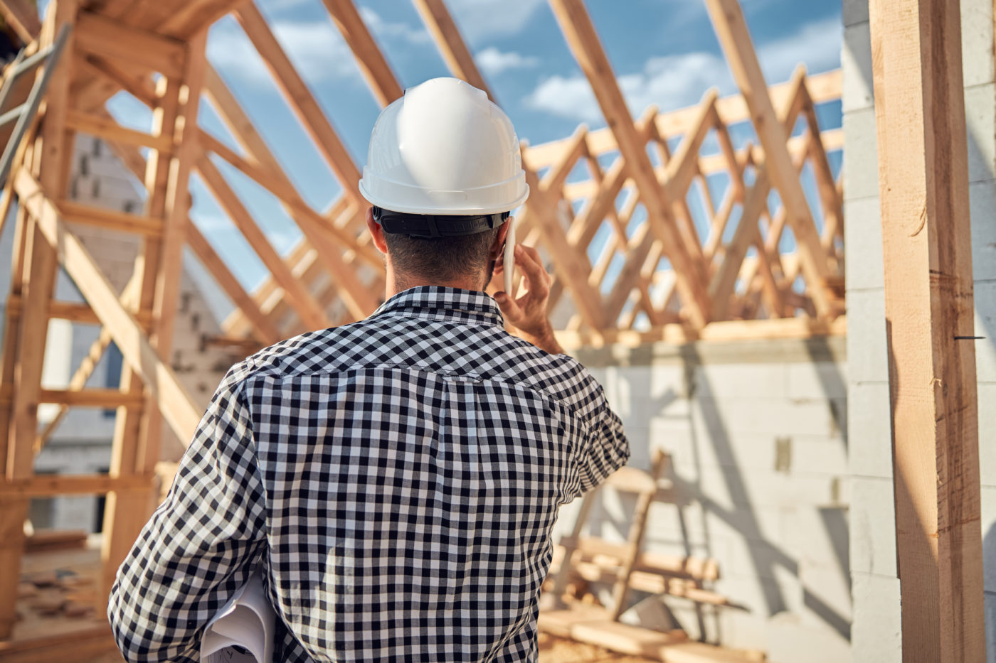 Young contractor in a hard hat talking on the phone