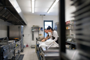Chef and cook working on their dishes indoors in restaurant kitchen.