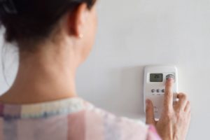 Woman is adjusting thermostat settings