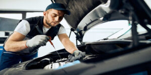 Auto repairman examining car oil while working in a repair shop.