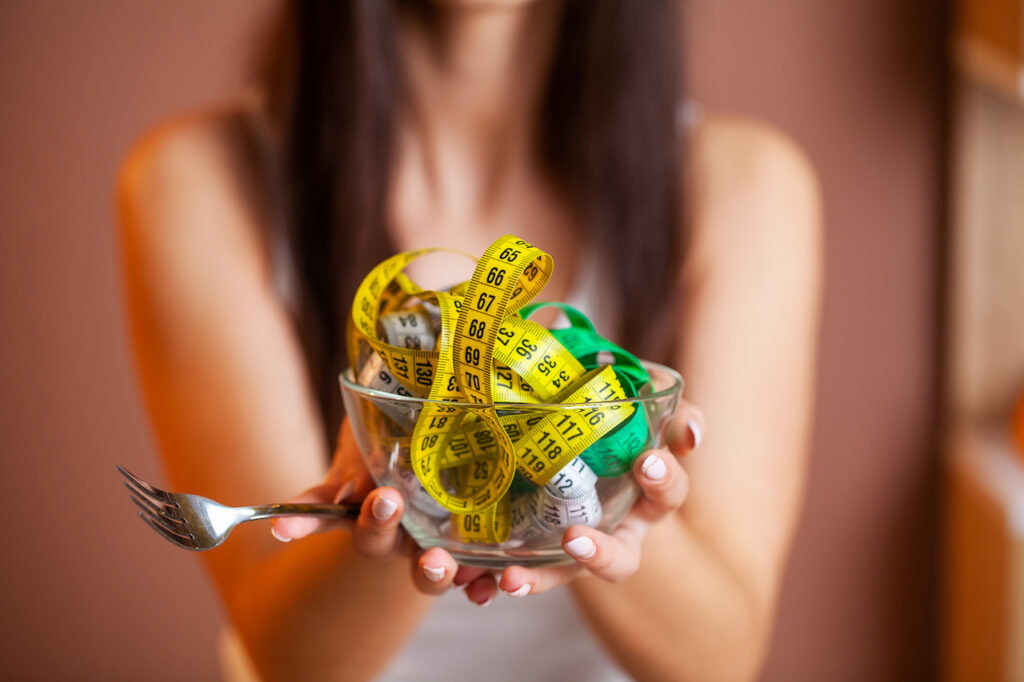 Cute woman on a diet holding a plate full of tape.